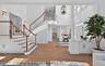 Grand foyer featuring a curved staircase with natural wood handrails and white balusters