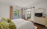 Bedroom featuring dark wood-finish flooring and direct access to a balcony through French doors