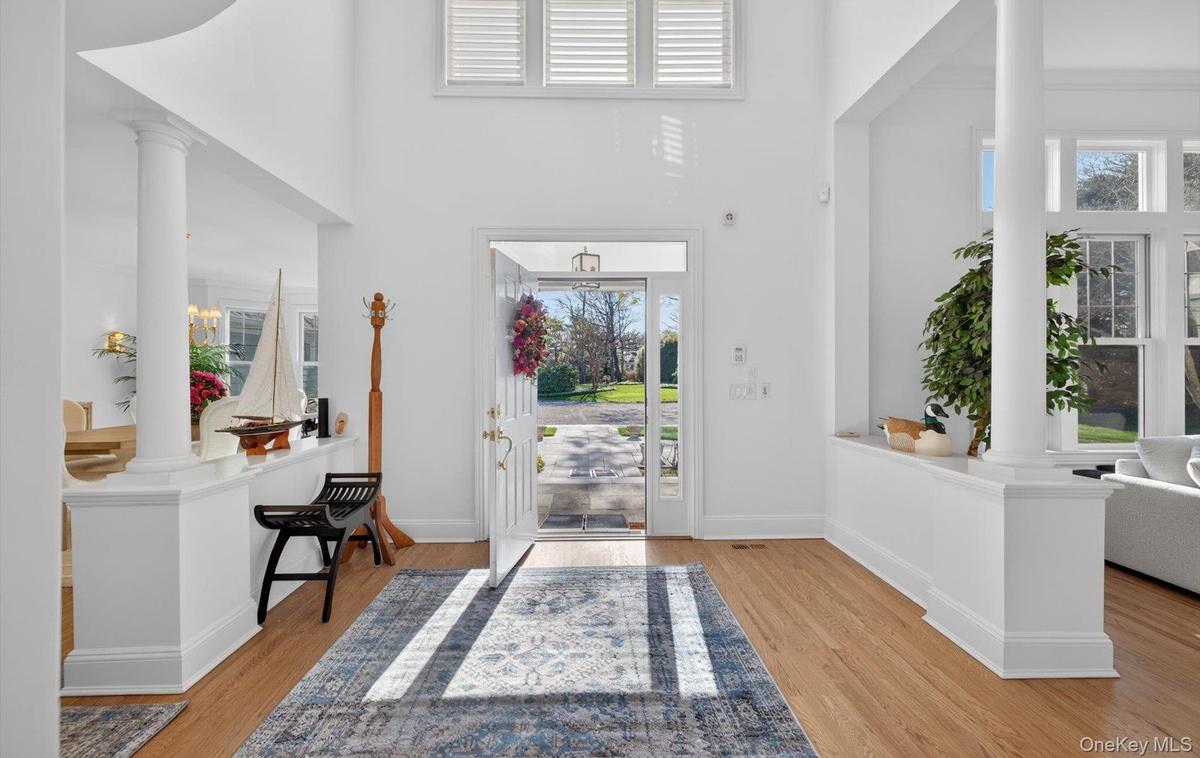 Grand entryway featuring a soaring ceiling, wood-finish flooring, and white interior columns