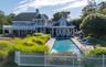 Expansive outdoor living area featuring a rectangular in-ground pool with surrounding patio, a separate hot tub, and a two-story residence with multip