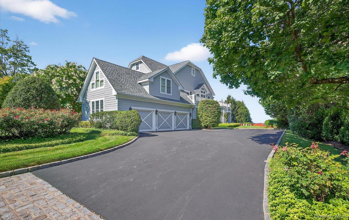 Shingle-style residence featuring light gray siding and a dark shingle roof