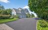 Shingle-style residence featuring light gray siding and a dark shingle roof