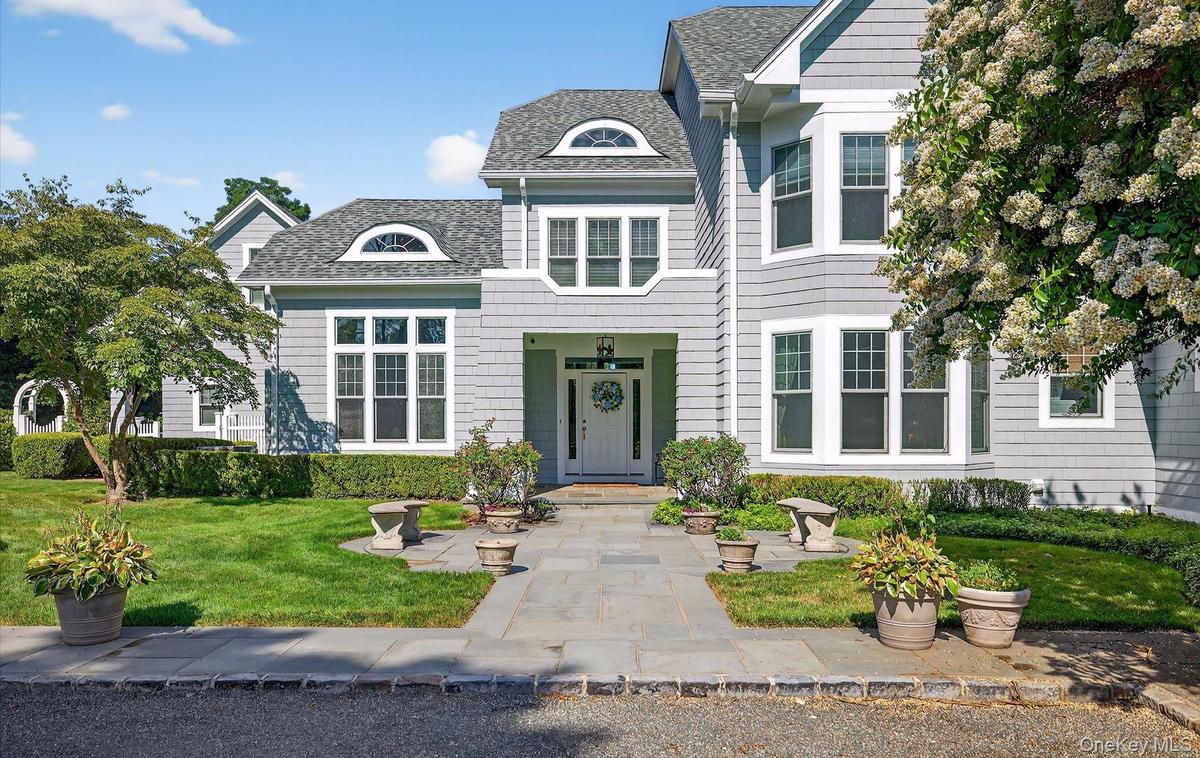 Traditional-style residence featuring light gray siding, white trim, and a prominent front entry with a transom window