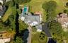 Expansive property featuring a multi-level residence with a gray shingle roof, a rectangular in-ground pool, a circular patio, mature perimeter planti