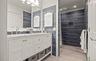 Dual vanity with white cabinetry, polished chrome fixtures, and a light-toned countertop