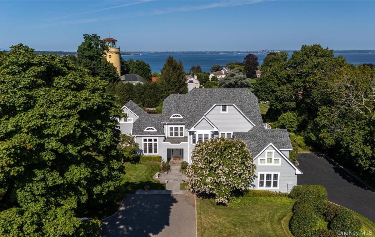 Gray shingle-style residence featuring a multi-gabled roofline, dormer windows, and a paved driveway