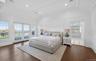 Spacious bedroom featuring dark wood-finish flooring, white paneling, and an ornate tray ceiling