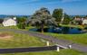 Expansive green lawn surrounds a serene pond with a central fountain feature