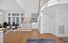 Two-story entry foyer featuring wood-finish flooring, a grand staircase with wood newel posts and handrails, and a second-story curved landing