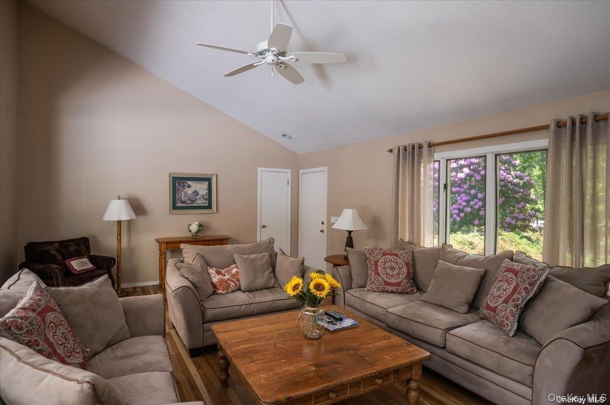 Living area featuring vaulted ceilings, wood-finish flooring, and a ceiling fan