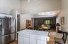 Open-concept kitchen and living area featuring a central island with storage, stainless steel refrigerator, wood-finish flooring, vaulted ceilings, an