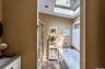 Bathroom featuring a jetted tub, glass-enclosed shower, skylight, and window with plantation shutters