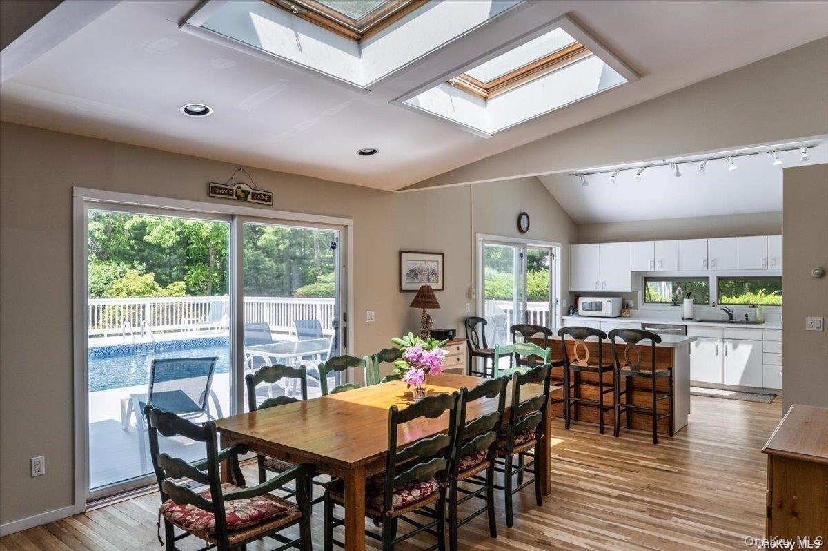 Vaulted ceilings featuring two skylights, recessed lighting, and wood-finish flooring
