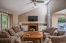Vaulted ceiling living area featuring hardwood flooring, built-in shelving, a fireplace with a wood mantle, and an outdoor deck with a pool
