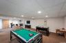 Spacious recreational room featuring recessed lighting, a drop ceiling, and wood-finish bi-fold doors