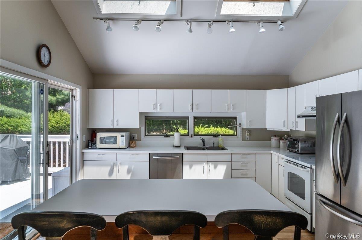 Kitchen featuring white cabinetry, stainless steel appliances, and a central island
