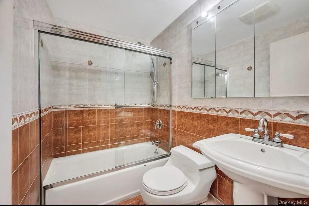 Bathroom featuring tile walls and shower / bath combination with glass door