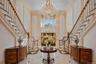Grand foyer featuring a dual staircase with wood handrails, a large multi-tiered chandelier, and polished tile flooring with contrasting accents