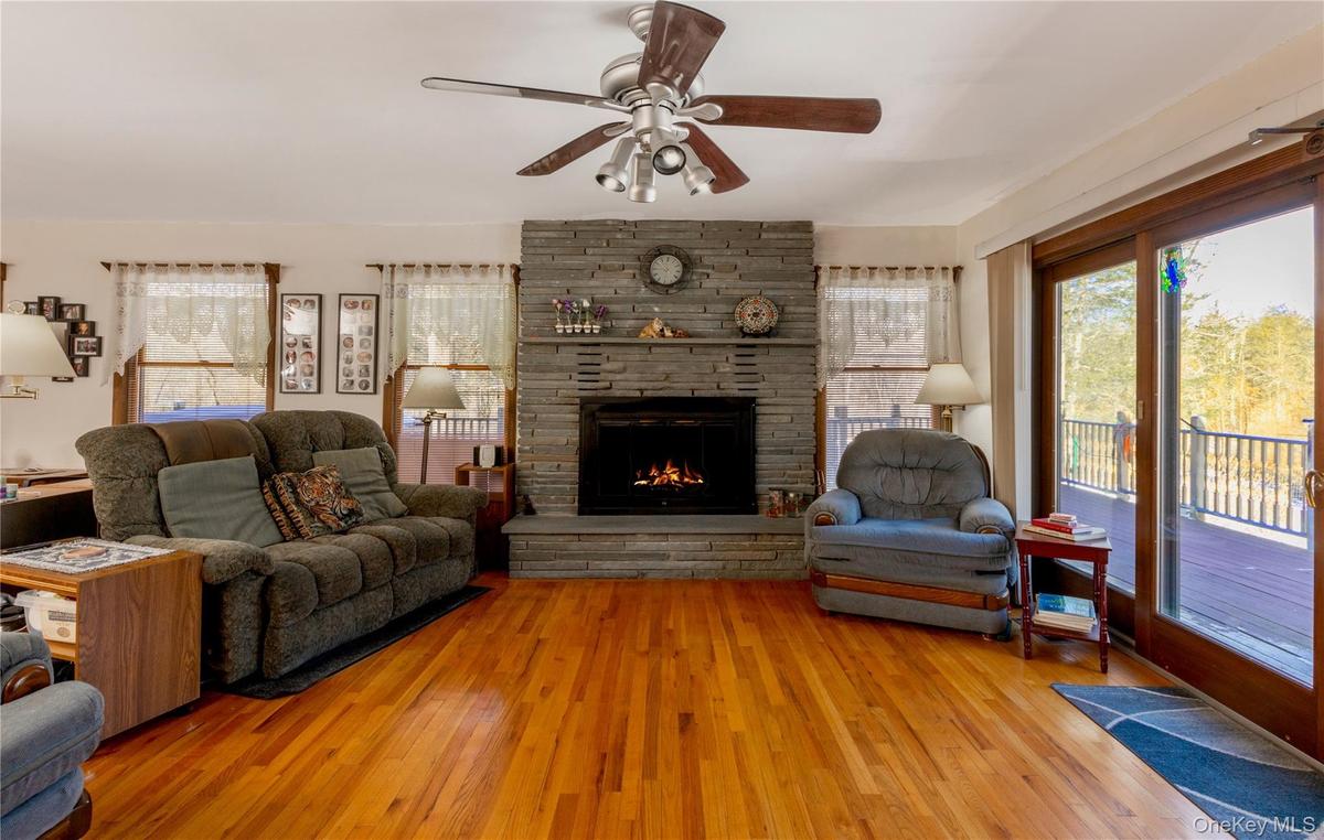 Hardwood flooring complements a stone-faced fireplace with hearth