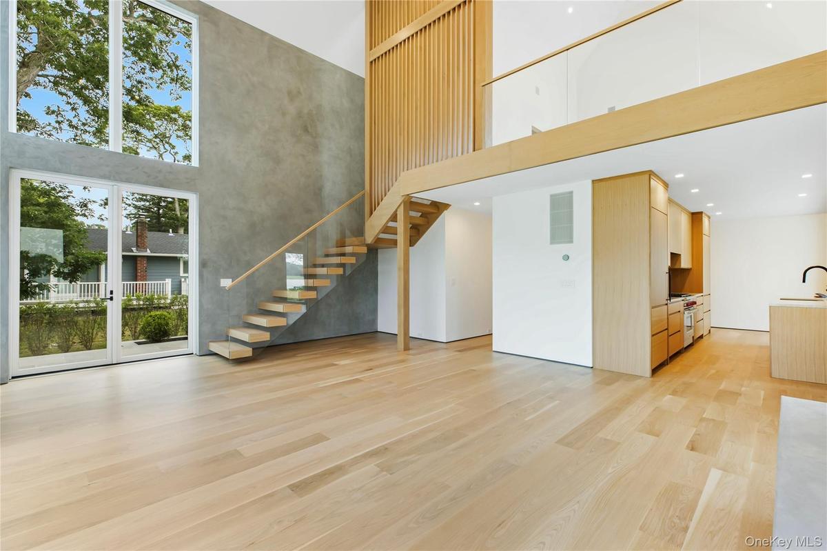 Unfurnished living room with a towering ceiling, light wood-type flooring, and stairway