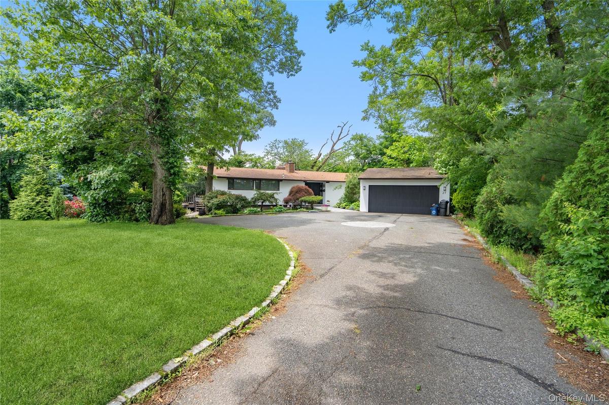 View of front of property featuring asphalt driveway, a front lawn, and a garage