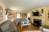 Living room featuring hardwood flooring, built-in shelving, a fireplace with a dark stone surround, and crown molding