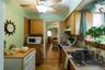 Galley kitchen featuring wood-finish flooring, wood cabinetry, light-toned countertops, and a stainless steel sink