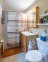 Bathroom featuring a single vanity with wood cabinetry, a white countertop, and a brass-finish faucet