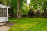 Expansive backyard featuring a manicured lawn, mature trees, and a privacy fence