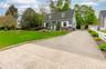 Cape Cod style home featuring a gabled roof, dormer windows, and white window shutters