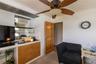 Integrated wet bar featuring a stainless steel sink, black countertop, mirrored backsplash, and glass shelving