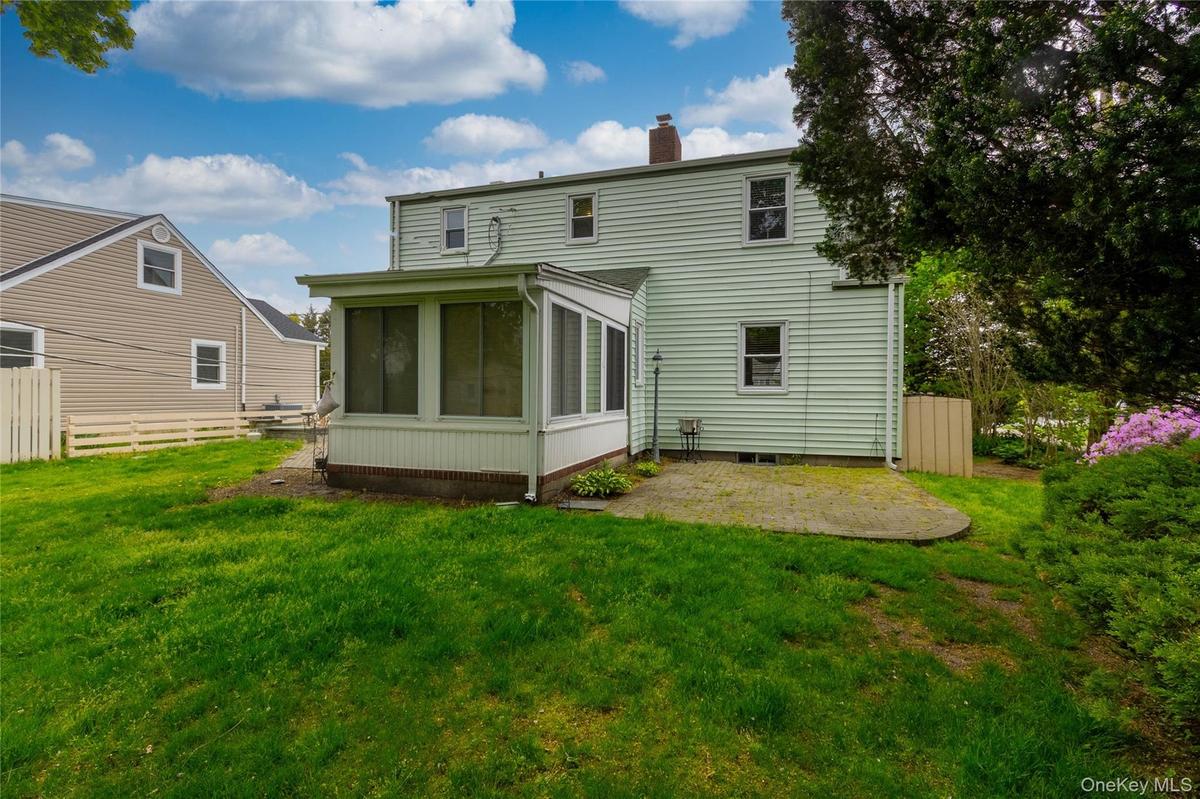 Rear exterior featuring light green siding, a screened-in porch with white trim, and a concrete patio