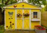 Bright yellow exterior shed with white trim, double entry doors, a side window with shutters, and an integrated window box