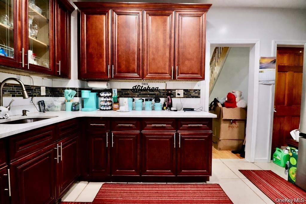 Kitchen with dark wood-finish cabinetry, light-toned countertops, and a dark mosaic tile backsplash