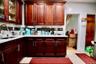 Kitchen with dark wood-finish cabinetry, light-toned countertops, and a dark mosaic tile backsplash