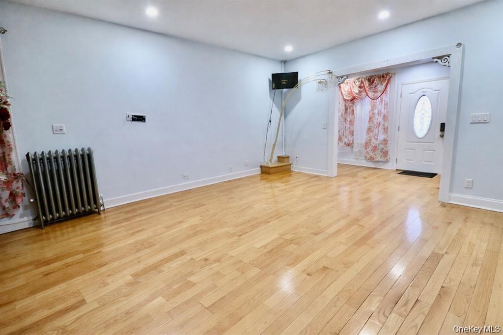 Spacious room featuring wood-finish flooring, recessed lighting, and a front entry door with an oval-shaped glass insert