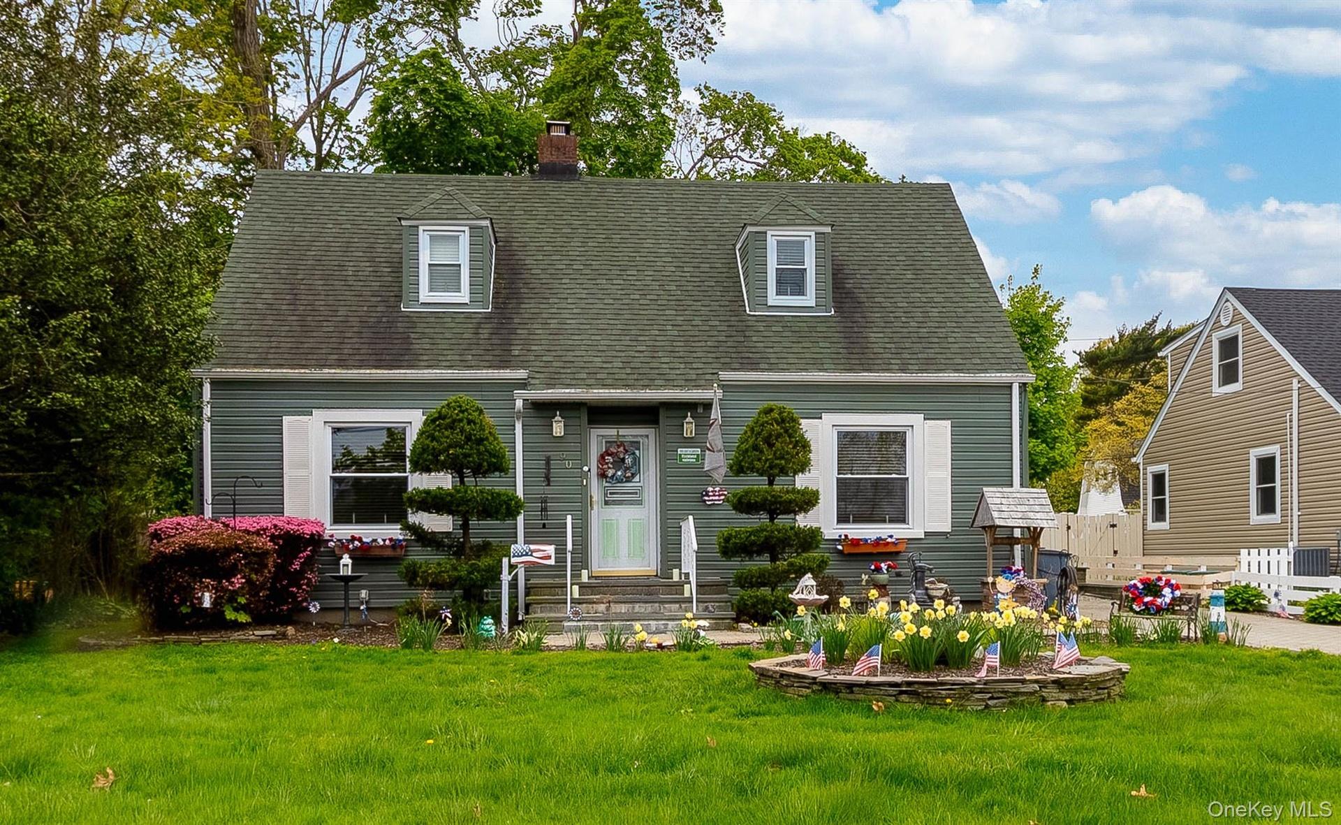 Dormer-style residence featuring green siding and a matching shingled roof