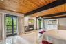 Bedroom with wood ceiling with exposed beams, access to outside, a stone fireplace, multiple windows, and baseboard heating