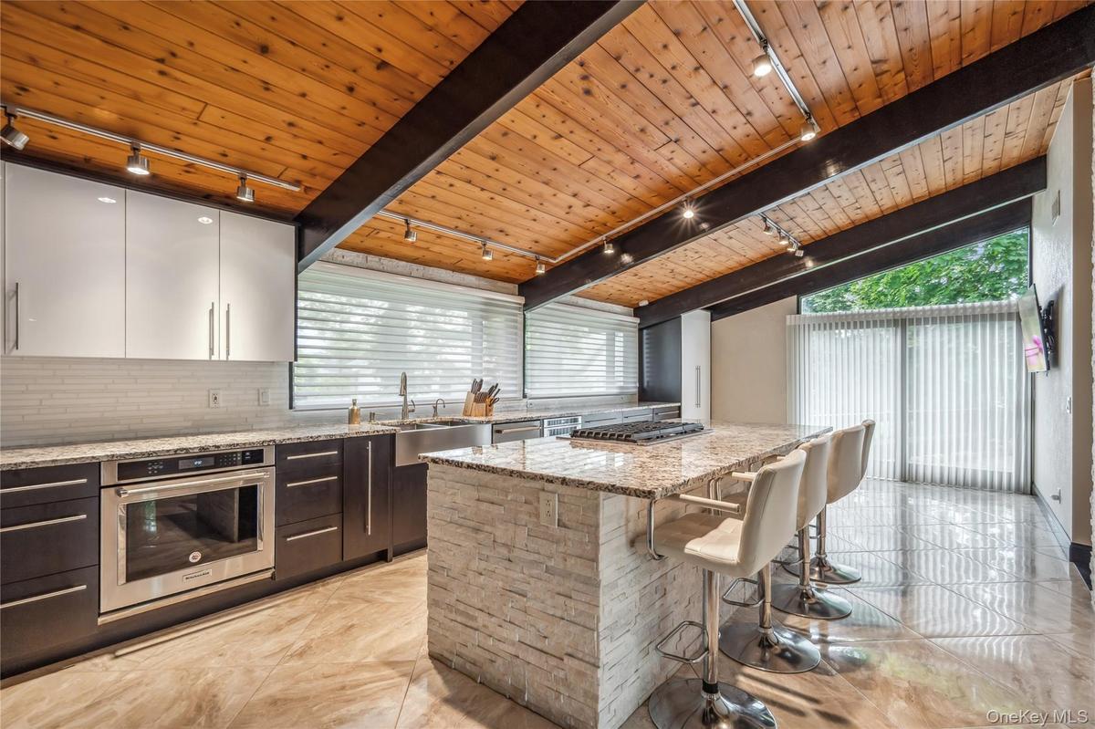 Kitchen featuring rail lighting, stainless steel appliances, a sink, and wooden ceiling