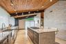 Kitchen with rail lighting, wood ceiling with exposed beams, a sink, light stone counters, and stainless steel gas stovetop