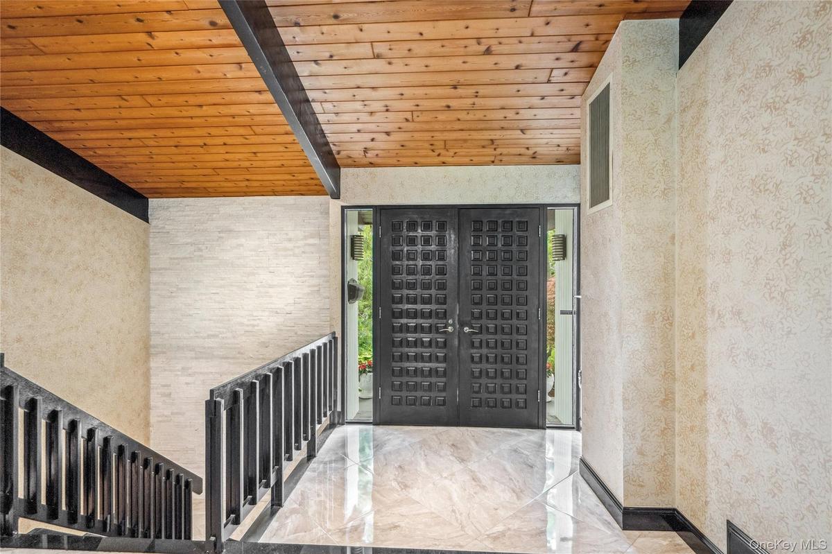 Entryway featuring wooden ceiling with exposed beams and marble tiled flooring