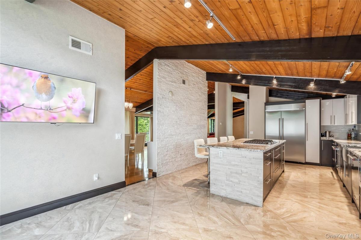 Kitchen featuring track lighting, wooden ceiling, appliances with stainless steel finishes, a center island, and modern cabinets