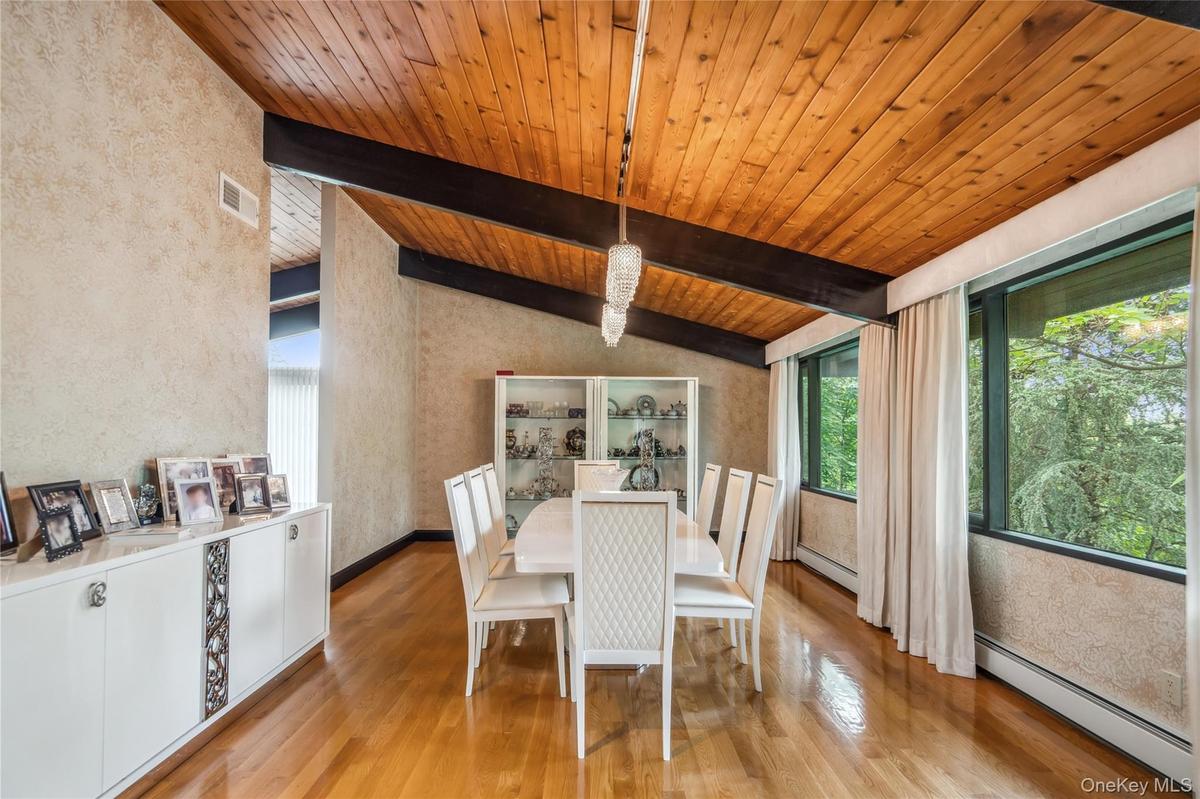 Dining area featuring a baseboard heating unit, wooden ceiling, light wood-style floors, a chandelier, and a textured wall