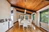 Dining area featuring a baseboard heating unit, wooden ceiling, light wood-style floors, a chandelier, and a textured wall