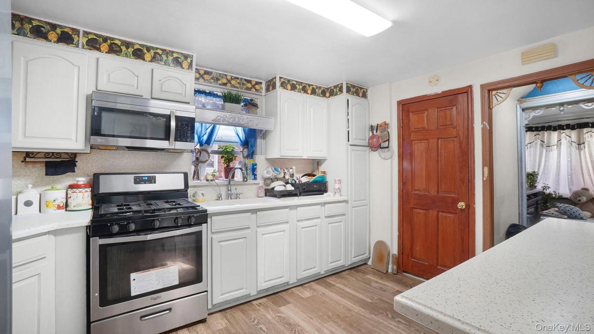 Kitchen featuring appliances with stainless steel finishes, light countertops, light wood-style flooring, and white cabinetry