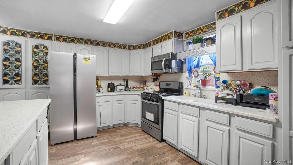 Kitchen featuring appliances with stainless steel finishes, light wood-style floors, and white cabinetry