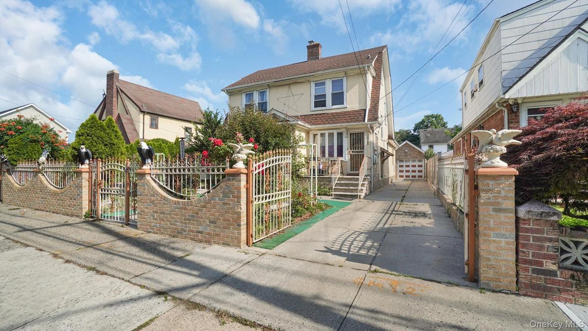 View of front of property featuring a gate, a fenced front yard, a detached garage, and a chimney