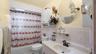 Bathroom featuring tile walls, shower / bathtub combination with curtain, vanity, a wainscoted wall, and tile patterned flooring