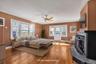 Large Primary Suite featuring hardwood flooring, multiple windows, a ceiling fan, a fireplace, and an exterior door to the rooftop.