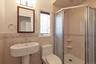 Primary Bathroom, featuring a corner shower stall with glass enclosure, a pedestal sink with a chrome faucet, a wall-mounted mirror, ceramic wall tili